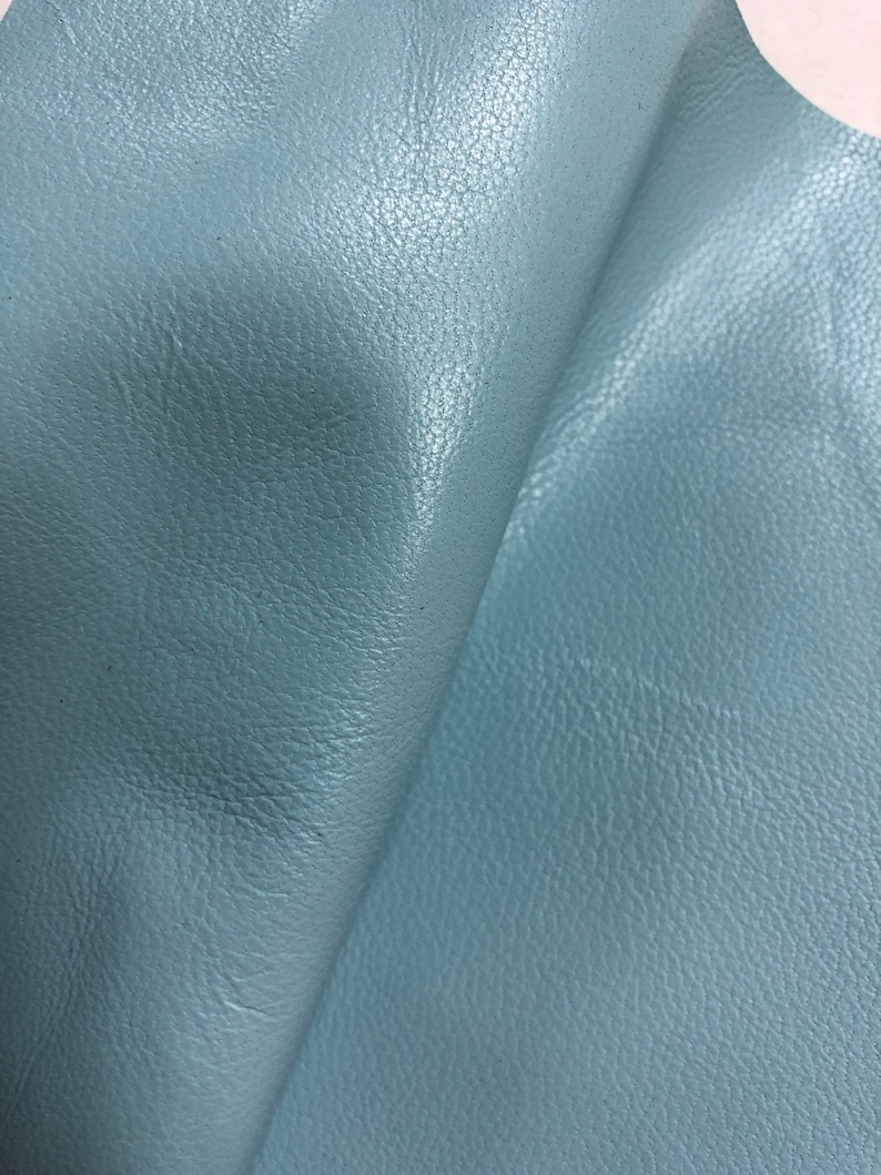 May include: A close-up of a piece of light blue leather with a textured surface.