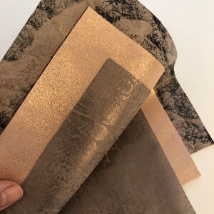 May include: Three sheets of faux leather in different colors and patterns. The top sheet is a light brown with a glittery finish. The middle sheet is a dark brown with a snakeskin pattern. The bottom sheet is a dark brown with a speckled pattern.