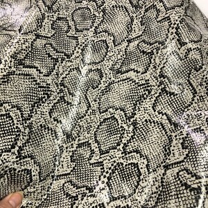 May include: Close-up of a white and black snakeskin fabric with a textured pattern.