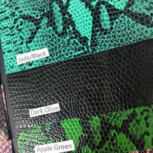May include: Close-up of three different colored faux snakeskin fabric swatches. The swatches are labeled "Jade/Black", "Dark Olive", and "Apple Green".