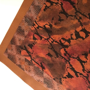 May include: Close-up of a brown leather fabric with a snakeskin pattern. The fabric has a textured surface and a subtle sheen.