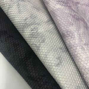 May include: Three fabric swatches in different colors and textures. The top swatch is a light purple with a subtle pattern. The middle swatch is a light gray with a textured pattern. The bottom swatch is black with a textured pattern.