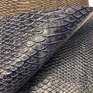 May include: Close-up of four different faux leather fabric swatches. The swatches are textured to resemble snakeskin. The swatches are in shades of teal, brown, dark blue, and black.