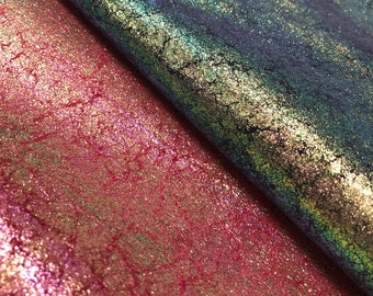 May include: Close-up of two pieces of textured fabric. One is a deep teal with gold accents, the other a shimmering magenta with gold and green highlights. The fabrics have a crackled, distressed appearance.