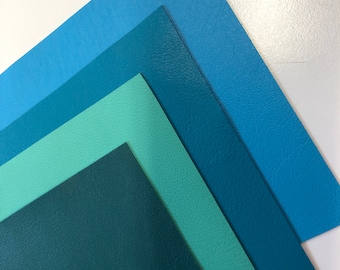 May include: Four sheets of faux leather in shades of blue and green. The sheets are stacked on top of each other, with the darkest green sheet on the bottom and the lightest blue sheet on top.