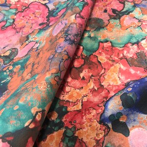 May include: Abstract fabric with a colorful watercolor design featuring shades of pink, orange, blue, and green.