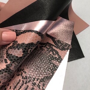 May include: Four different pieces of leather in various colors and textures. The leather is pink, black, metallic pink, and a pink snakeskin pattern.