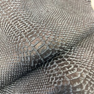 Puede incluir: Primer plano de una piel de serpiente azul oscuro con un patr&oacute;n texturizado y escamoso.