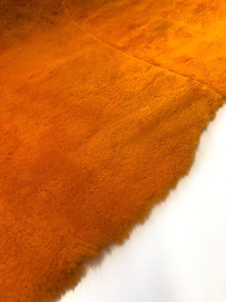 May include: Close-up of a piece of orange faux fur fabric. The fabric has a soft, fluffy texture.