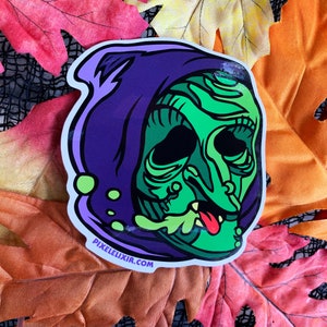 Könnte beinhalten: Ein grüner und lilafarbener Sticker einer Hexe mit einem tropfenden grünen Gesicht und einem lilafarbenen Kapuzenumhang. Der Sticker hat den Text "pixelelixir.com" unten.