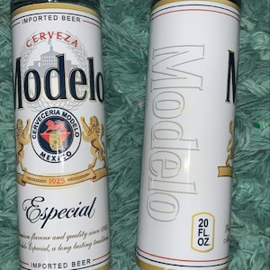 May include: Two white insulated tumblers with a Modelo Especial beer logo. The logo features a lion, a barrel, and the text "Cerveceria Modelo Mexico 1925". One tumbler has the text "Especial" and "Imported Beer" printed below the logo. The other tumbler has the text "20 fl oz" printed below the logo.