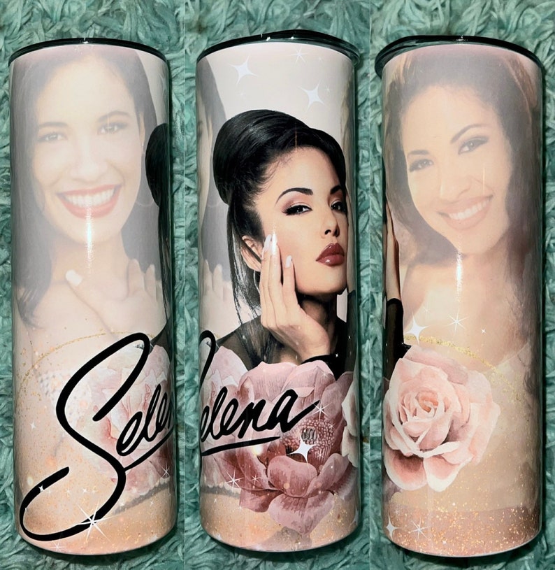 May include: A white stainless steel tumbler with a pink rose and glitter design. The tumbler features a photo of Selena and her signature in black.