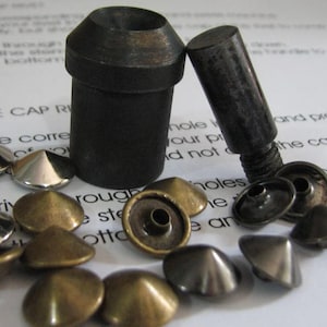 May include: A collection of metal rivets and tools for leathercraft. The image shows silver, brass, and dark metal rivets in various shapes, along with a setting tool and a screw. The items are on a white surface with text.