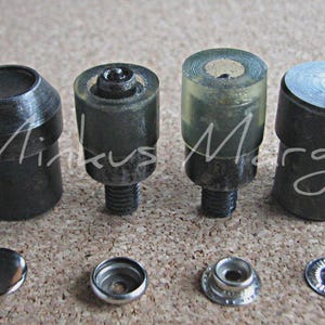 May include: A collection of metal tools and fasteners, including several cylindrical pieces with threaded bases and various shapes. The image also shows several snap fasteners. The text "Minkus Margo" is visible in the image.