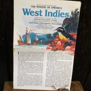 May include: A vintage National Geographic Magazine cover titled "West Indies." The cover features a painting of a sailing ship, a bird, and tropical foliage. The magazine is open, revealing text about the history of the West Indies.