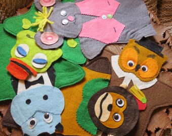 Könnte beinhalten: Eine Sammlung farbenfroher Tierformen aus Filz, darunter eine Eule, ein Frosch und ein Nilpferd, mit Wackelaugen und anderen Details. Die Filzstücke sind in einer Holzschale angeordnet, mit einer neutralfarbenen Strickdecke im Hintergrund.