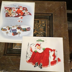 May include: Two vintage Christmas cards. One card shows Santa Claus in a sleigh with gifts, flying over a snowy village. The other card depicts Santa in bed dreaming of a green car. Both cards have a festive, retro design.