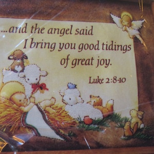 May include: A Christmas-themed cross-stitch pattern featuring a nativity scene with the text "...and the angel said I bring you good tidings of great joy. Luke 2:8-10." The image includes an angel, baby Jesus, sheep, and other animals.