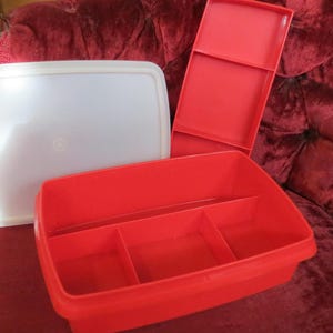 Könnte beinhalten: Ein Set aus Vintage-Kunststoff-Aufbewahrungsbehältern. Das Set enthält einen weißen rechteckigen Deckel, einen roten geteilten Behälter und einen roten Deckel. Die Behälter bestehen aus strapazierfähigem Kunststoff.