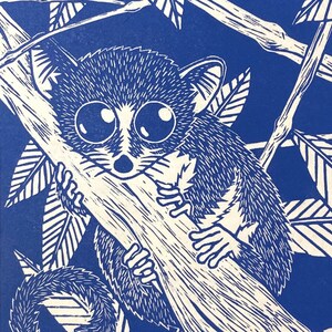Peut inclure: Une estampe sur bois bleue et blanche représentant un lémurien accroché à une branche. Le lémurien a de grands yeux et une longue queue. L'estampe est intitulée "Le Microcebe de la Berthe" et signée "Takamura Shido".