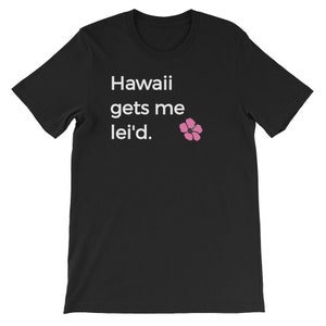 May include: Black t-shirt with white text that reads "Hawaii gets me lei'd." A pink hibiscus flower is to the right of the text.