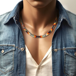 Puede incluir: Un collar de cuentas con un patrón geométrico en tonos de gris, negro, naranja y rojo.