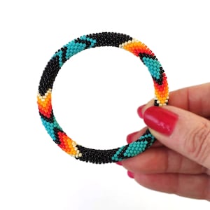May include: A colourful beaded bracelet with a black, turquoise, orange and yellow pattern.