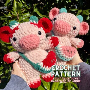 Pode incluir: Dois peluches de vaca rosa em croch&ecirc; com detalhes vermelhos e verdes. Cada vaca segura uma fatia de fruta em croch&ecirc;, uma melancia e um morango. O texto "CROCHET PATTERN FRUIT SLICE COWS HANDMADE BY ANNIE" est&aacute; na parte inferior da imagem.