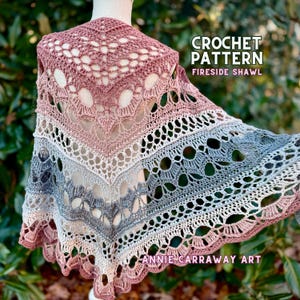 May include: A crochet shawl pattern called "Fireside Shawl" by Annie Carraway Art. The shawl is a gradient of pink, beige, and gray with a lacy design.