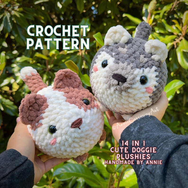 May include: Two handmade crochet dog plushies. One is white and brown, the other is gray and white. Both have black eyes and pink cheeks. The text "CROCHET PATTERN" is at the top. The text "14 IN 1 CUTE DOGGIE PLUSHIES HANDMADE BY ANNIE" is at the bottom.