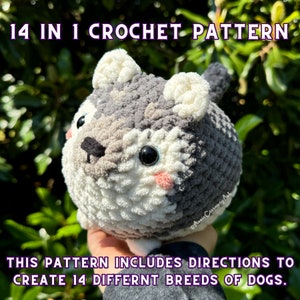 May include: A crocheted dog pattern with the text "14 IN 1 CROCHET PATTERN." The plush dog is gray, white, and black, with pink cheeks and large black eyes. The pattern includes directions to create 14 different dog breeds.