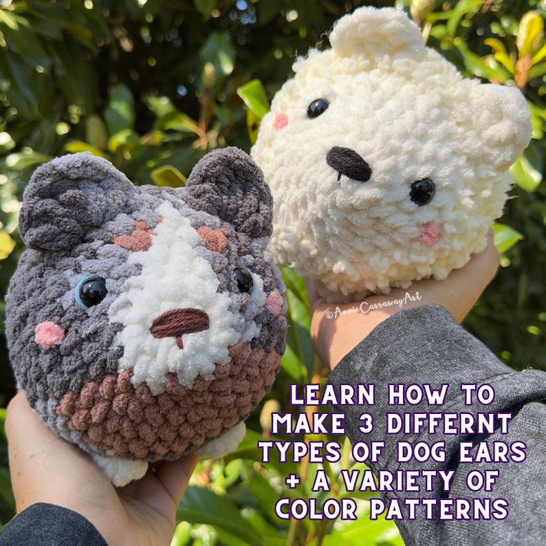 May include: Two handmade crochet dog-shaped plushies. One is gray, white, and brown, the other is white. Both have black eyes and pink cheeks. The image includes text that reads: "LEARN HOW TO MAKE 3 DIFFERENT TYPES OF DOG EARS + A VARIETY OF COLOR PATTERNS."
