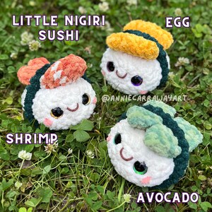 May include: Three crocheted sushi pieces: shrimp, egg, and avocado. Each has a white rice base, dark green seaweed, and colorful toppings. The sushi have smiling faces and are set on a bed of green grass. Text reads "Little Nigiri Sushi".