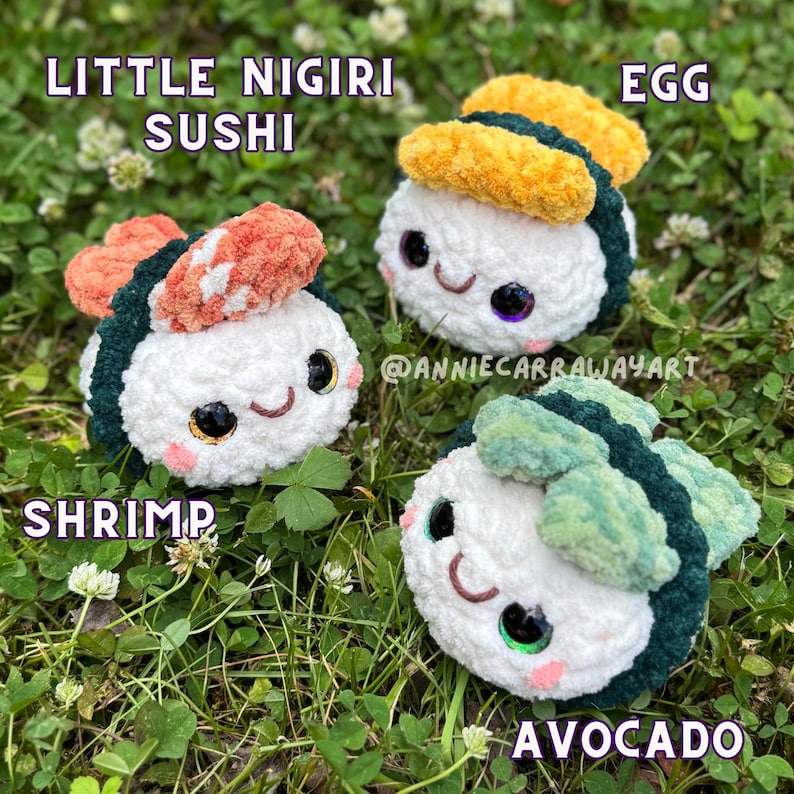 May include: Three crocheted sushi pieces: shrimp, egg, and avocado. Each has a white rice base, dark green seaweed, and colorful toppings. The sushi have smiling faces and are set on a bed of green grass. Text reads "Little Nigiri Sushi".