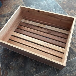 May include: A wooden crate with a slatted bottom. The crate is made of natural wood and has a light brown color.