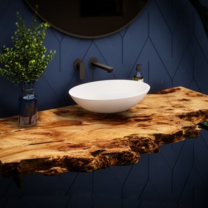 Könnte beinhalten: Ein weißes Keramik-Waschbecken sitzt auf einer rustikalen Holz-Arbeitsplatte mit einer lebenden Kante. Die Arbeitsplatte ist an einer dunkelblauen Wand mit geometrischem Muster befestigt. Ein schwarzer Wasserhahn ist an der Wand hinter dem Waschbecken befestigt.