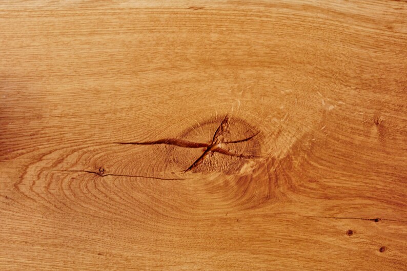May include: Close-up of a light brown wood surface with a knot in the center. The wood grain is visible and the surface is smooth.