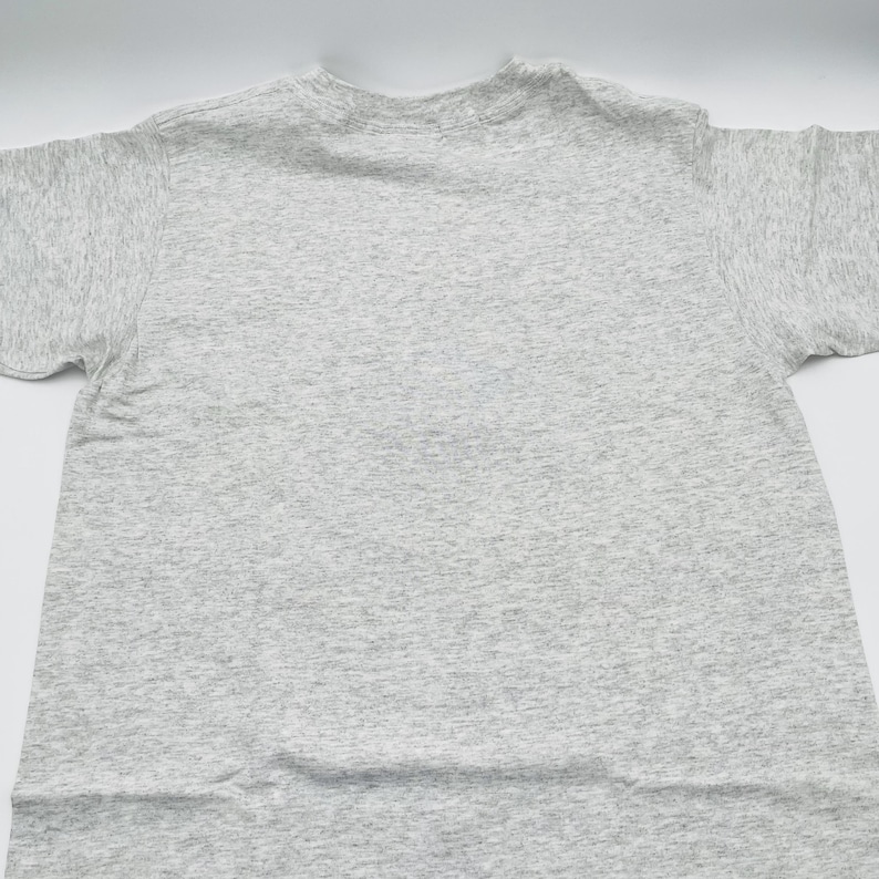 May include: A short-sleeved t-shirt in a light heather gray color. The garment features a classic crew neckline and a standard fit with visible fabric texture throughout. The material has a speckled appearance with darker gray flecks.