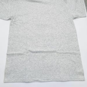 May include: A short-sleeved t-shirt in a light gray heathered fabric. The garment features a classic crew neckline and a standard straight hemline. The material displays a subtle speckled texture throughout, consistent with a heathered cotton blend.