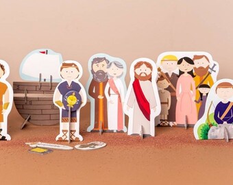 Puede incluir: Un conjunto de 14 figuras de cartón para colocar de pie que representan personajes y escenas bíblicas. Las figuras incluyen a Jesús, una tienda de campaña, un barco, una torre y varias personas.