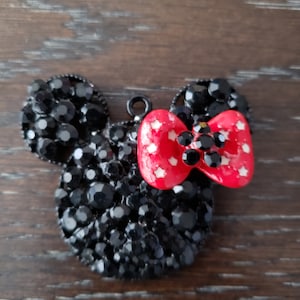 May include: Black rhinestone Mickey Mouse head charm with a red bow with white polka dots.