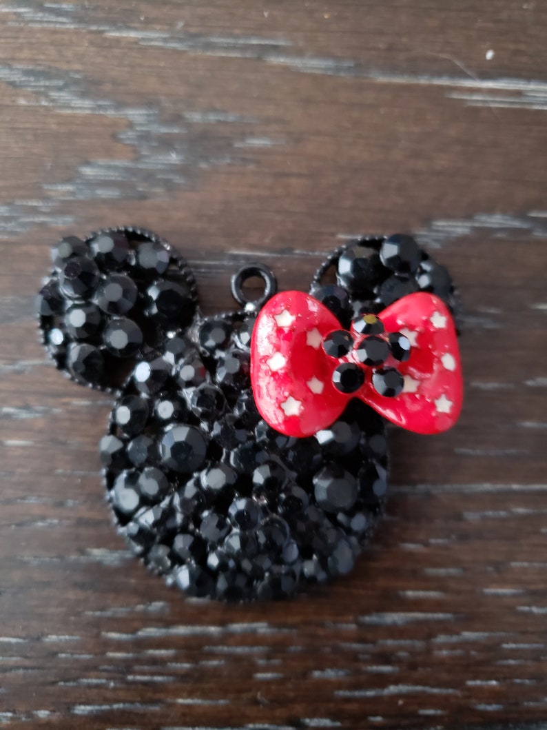 May include: Black rhinestone Mickey Mouse head charm with a red bow with white polka dots.