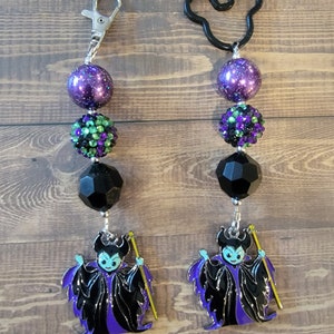 May include: Two beaded keychains. One has a silver clasp, the other a black Mickey Mouse shape. Each keychain features purple, green, and black beads, and a charm of a cartoon villain in black and purple robes, holding a yellow staff.
