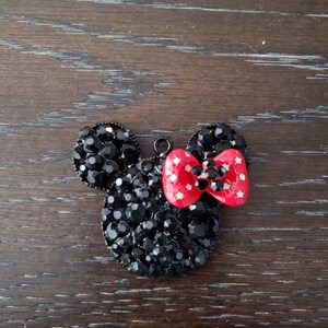 May include: Black rhinestone Mickey Mouse head charm with a red bow with white polka dots.