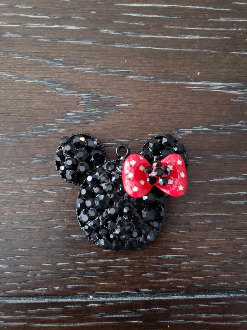May include: Black rhinestone Mickey Mouse head charm with a red bow with white polka dots.