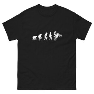 May include: Black t-shirt with a white graphic depicting human evolution, ending with a person on a motorcycle. The design shows the stages of development from ape to a motocross rider.