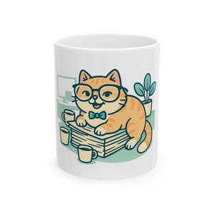 May include: A white ceramic mug featuring a graphic illustration of an orange tabby cat wearing black glasses and a teal bow tie. The cat is resting on a stack of papers surrounded by three small mugs, a computer monitor, and a potted plant.