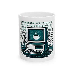 May include: A white ceramic mug featuring a dark teal graphic of a vintage computer with a coffee cup icon on the screen. The design includes binary code, circuit board patterns, and two floppy disks flanking the computer base on the mug surface.