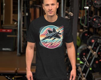 May include: A black t-shirt with a retro-style graphic of a fighter jet flying through the clouds. The graphic features a sunset with pink, orange, and yellow colors.