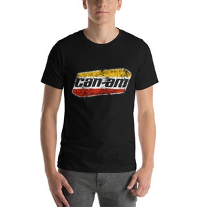 Op de afbeelding: Zwart T-shirt met een vintage "can-am" logo in rood, geel en wit.